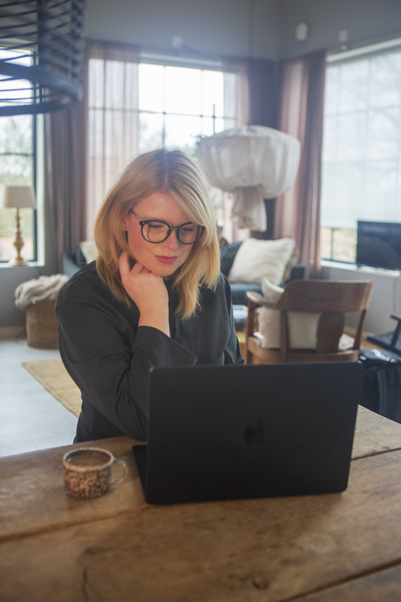 en kvinna med glasögon som sitter framför en dator.